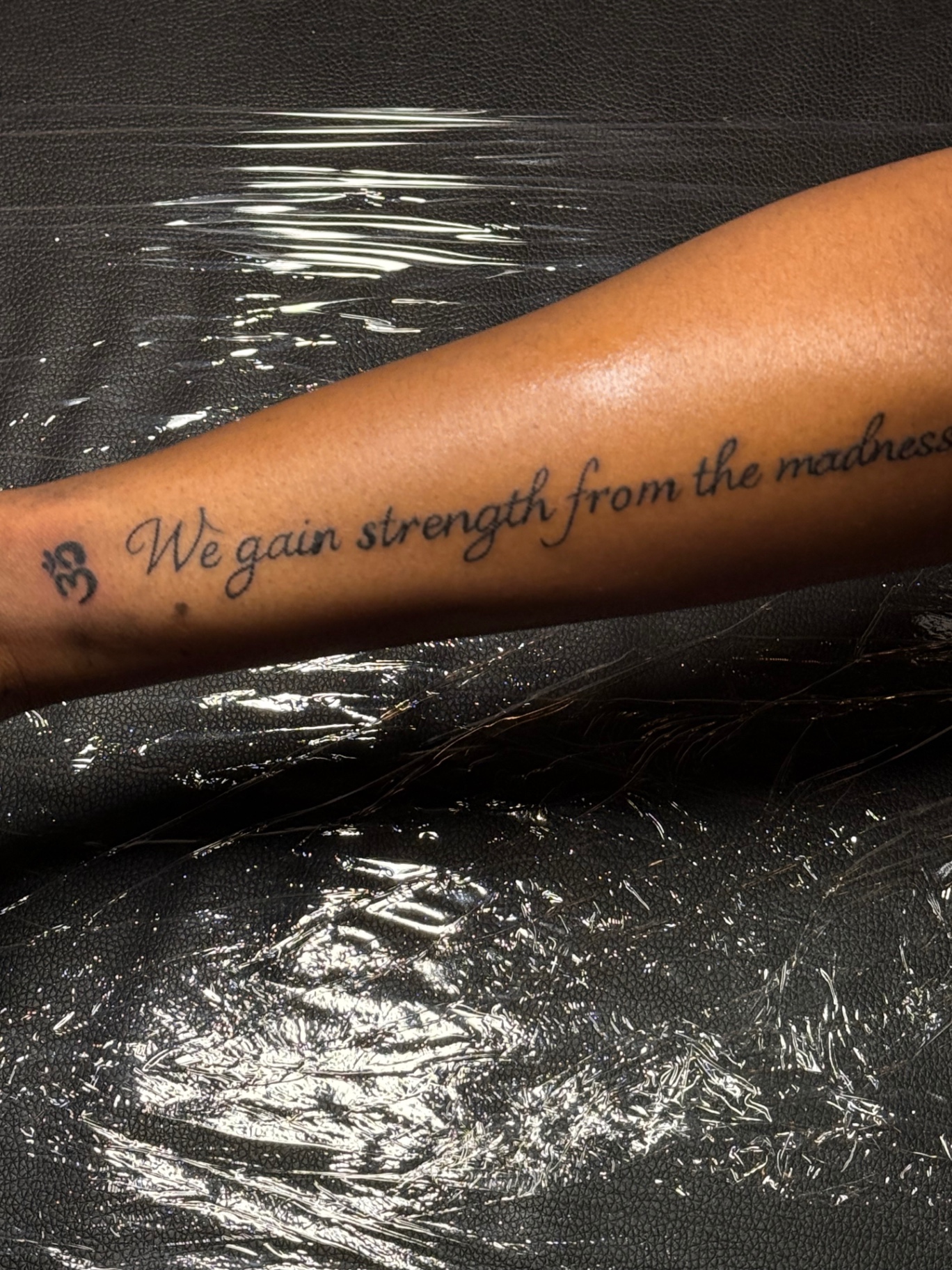 We gain strength from the madness script forearm tattoo