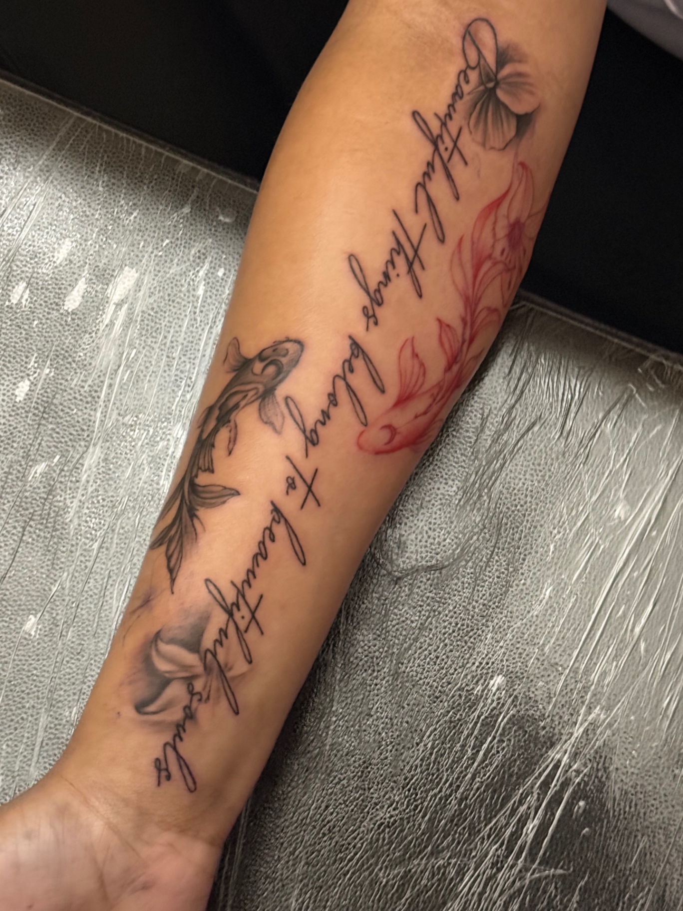 Koi fish, flowers and script forearm tattoo